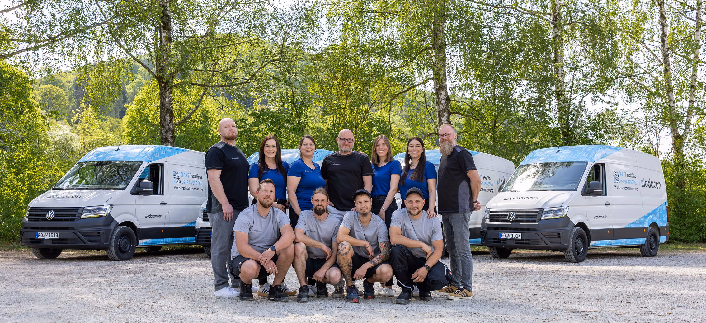 Teamfoto vor zwei Fahrzeugen von wodoacon im Freien, bestehend aus zwölf Personen in Arbeitskleidung